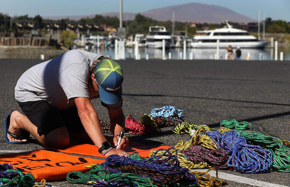 Ironman staff member Tim Dale marks bags while organizing ropes for river marker buoys in the parking lot of the Columbia Point Marina Park in Richland.