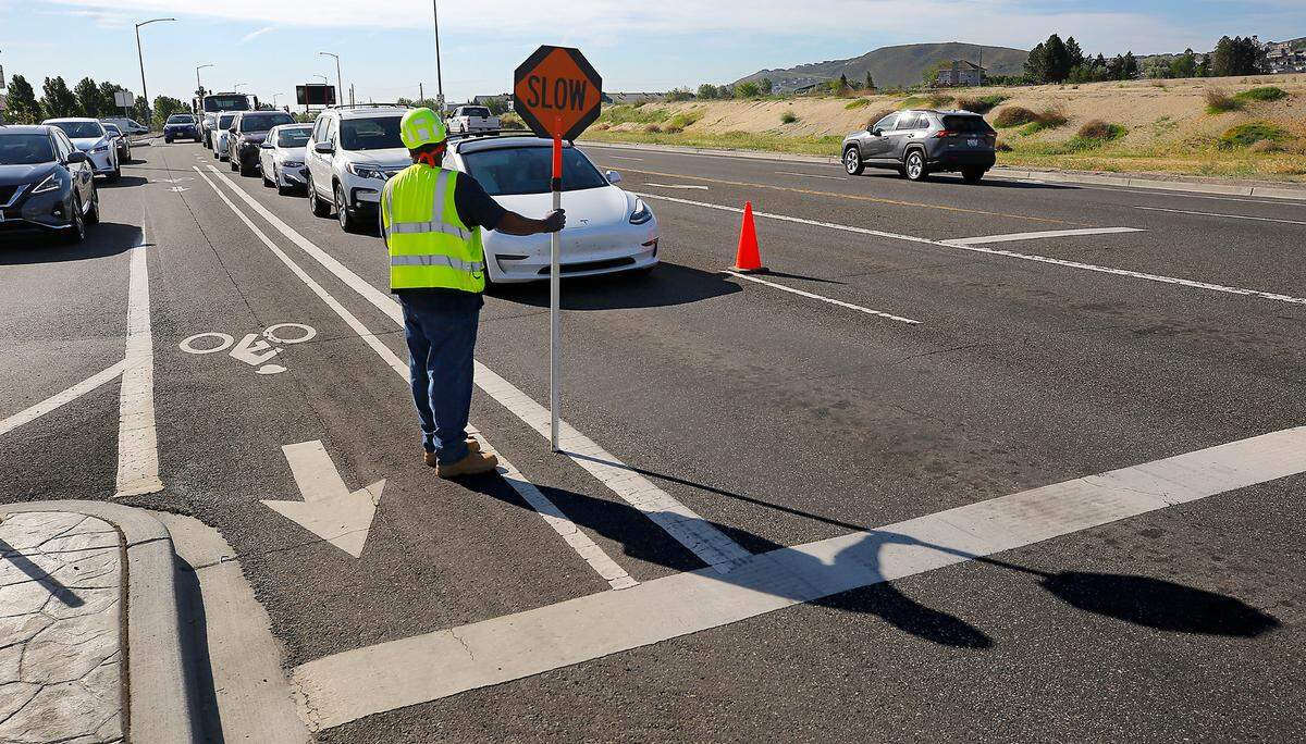 Traffic flagger Jasiri Sims, an employee of Pavement Surface Control, stops traffic on Keene Road Wednesday morning as other workers and Richland officials prepare to open the Queensgate Drive extension in south Richland.