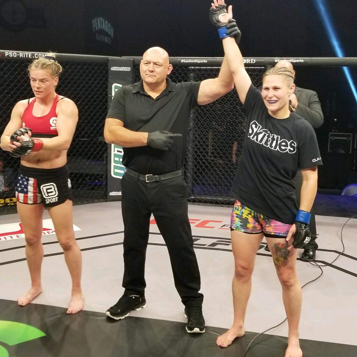 Referee Vance Swerden raises the arm of Kennewick’s Kelly Clayton on Friday to signify she won her MMA fight against Hailey Cowan.