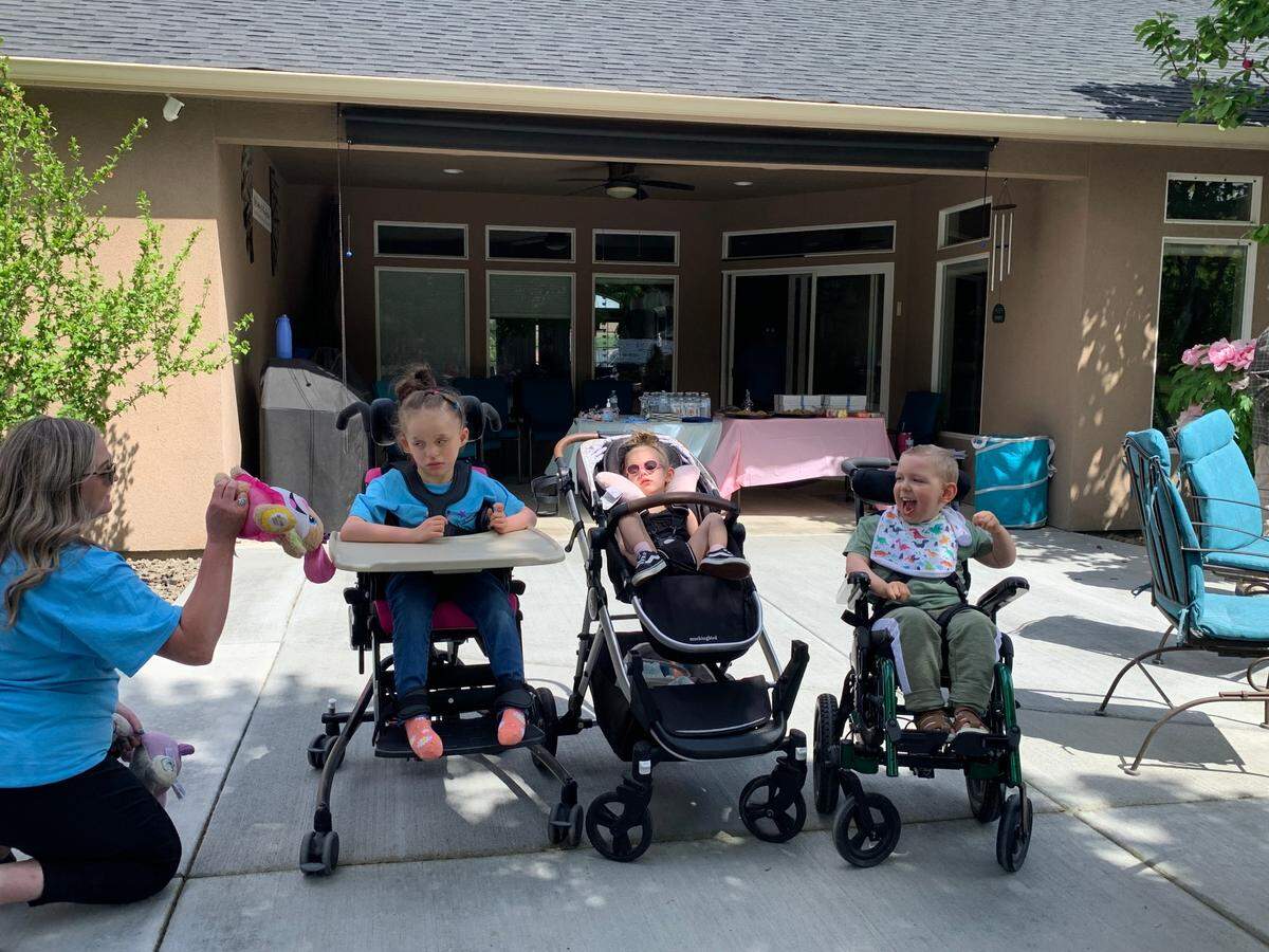 Finnley Couchman awaits the new playhouse ribbon-cutting with Millie George and Kade Korstvedt. All three are Wishing Star kids.