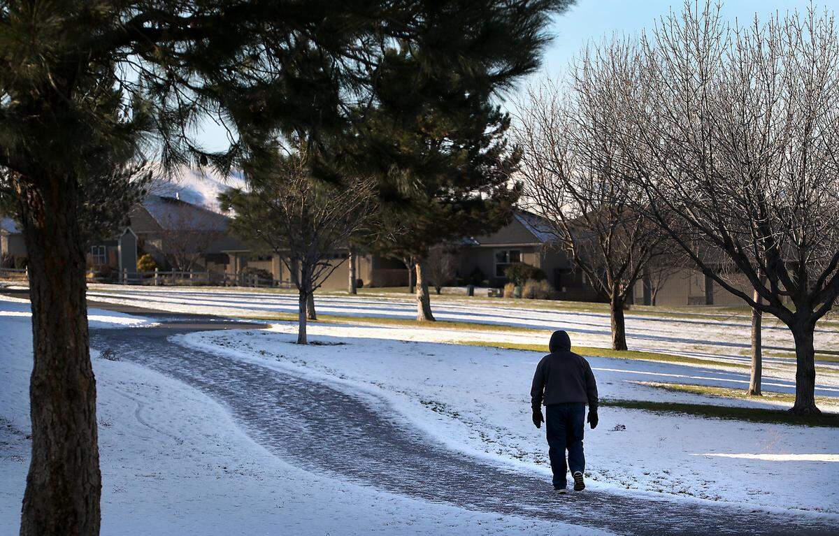 A walker carefully navigates the heavily shaded pathway in Kennewick’s Hansen Park that was still coated with snow and ice a day after an overnight surprise snowfall around much of the Mid-Columbia Basin.
