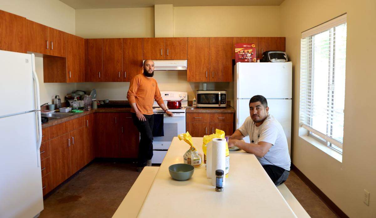 Marcos Gonzalez Rios and Rogaciano Sonchez Tapia talk in the kitchen of their unit at Ringold, a farmworker housing complex in Mesa, WA, owned by Wafla.