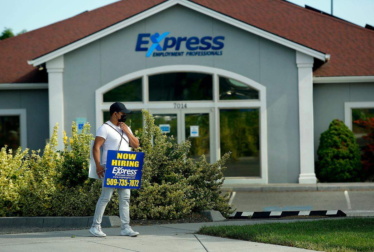 Darwin Largo, of Express Employment Professionals, tries to attract workers outside the staffing company office building on West Okanogan Place in Kennewick.
