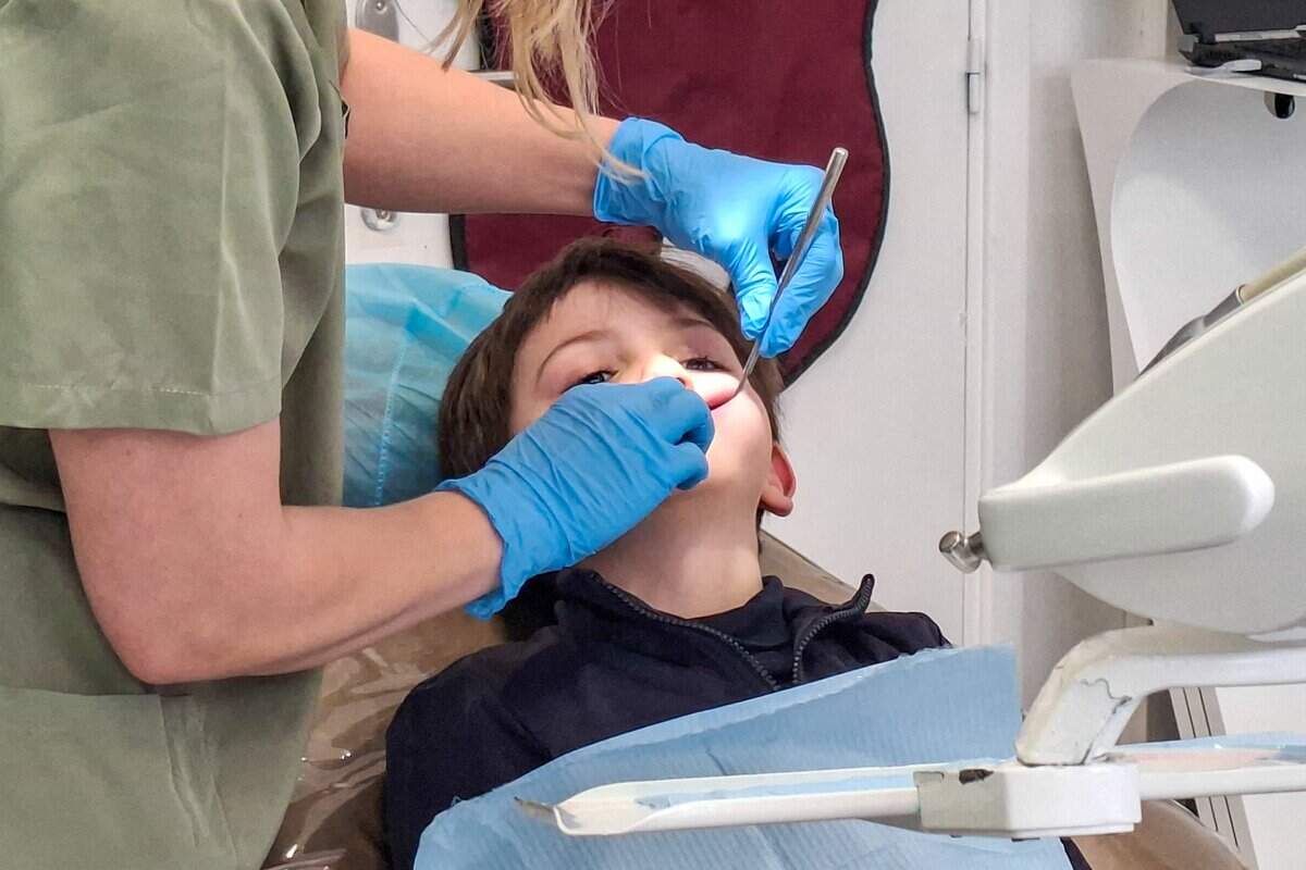 Dentist consulting with a young patient in a well-equipped dental practice, with medical equipment and treatment lighting visible around the chair in Paris, France, on February 23, 2026. Health, doctor, consultation, child. (Photo by Riccardo Milani / Hans Lucas / AFP via Getty Images)