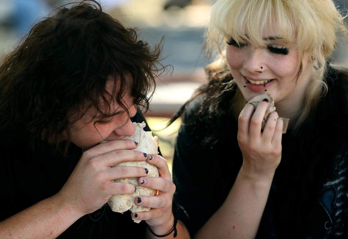 Aeribeth Nelson and her boyfriend, Nathan Brower, share bites of a loaded chicken burrito Tuesday at the Benton Franklin County Fair & Rodeo’s opening day in Kennewick. 