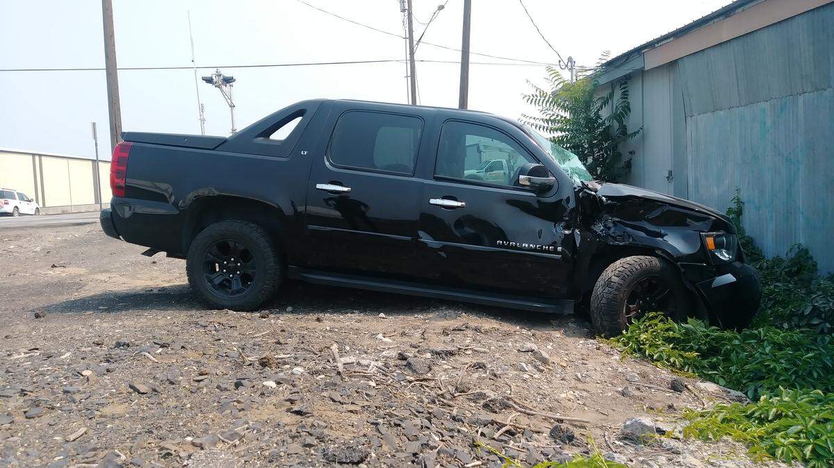 A Chevy Avalanche rests behind Dent Doctor after hitting a train Thursday on Fruitland Avenue in downtown Kennewick. The driver was not intoxicated, police said.