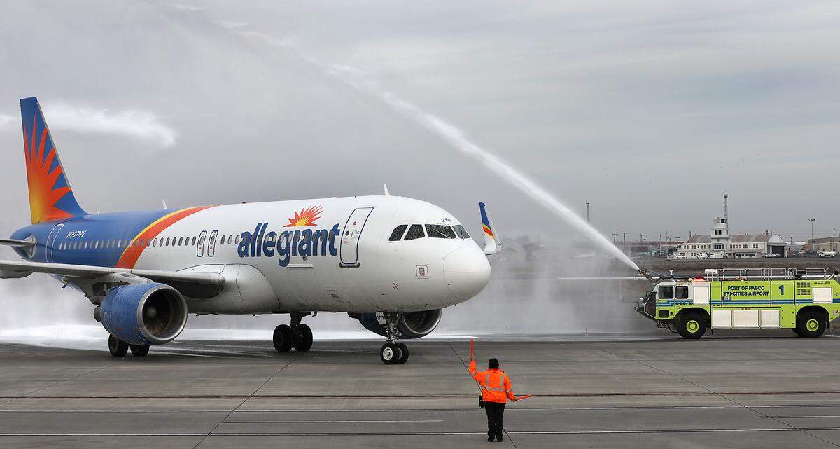 Pasco Fire Department aircraft firefighting trucks douse the Allegiant Airlines jet airplane with spray from their nozzles Thursday as it arrives at the Tri-Cities Airport in Pasco for its inaugural flight to Orange County, Calif.