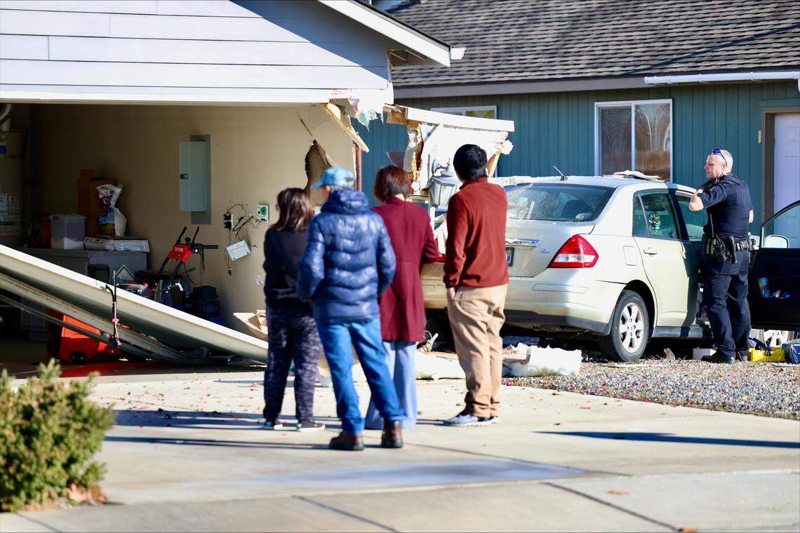Residents on the 5000 block of Wrigley Drive look on as Pasco police investigate a car that crashed into a garage on Friday.