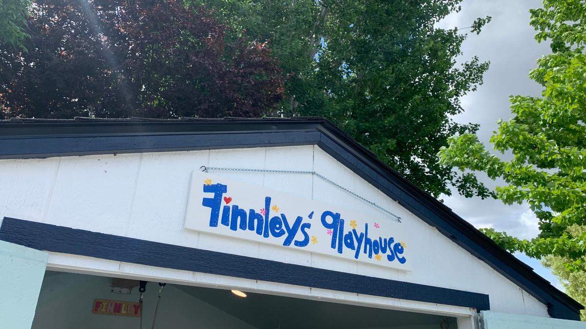 A sign at the playhouse entrance reads “Finnley’s Playhouse.” The structure was built by volunteers and the Wishing Star Foundation’s community partners for 4-year-old Finnley.