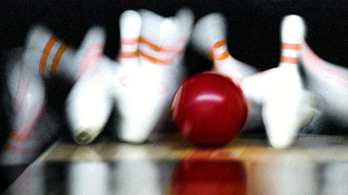 A bowling ball hits pins