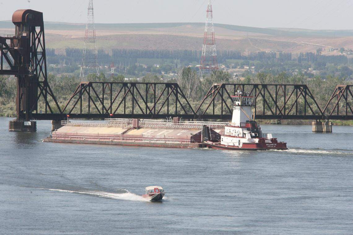 A barge and recreational boater pass each other on the Snake near Sacajawea Park in Pasco.
