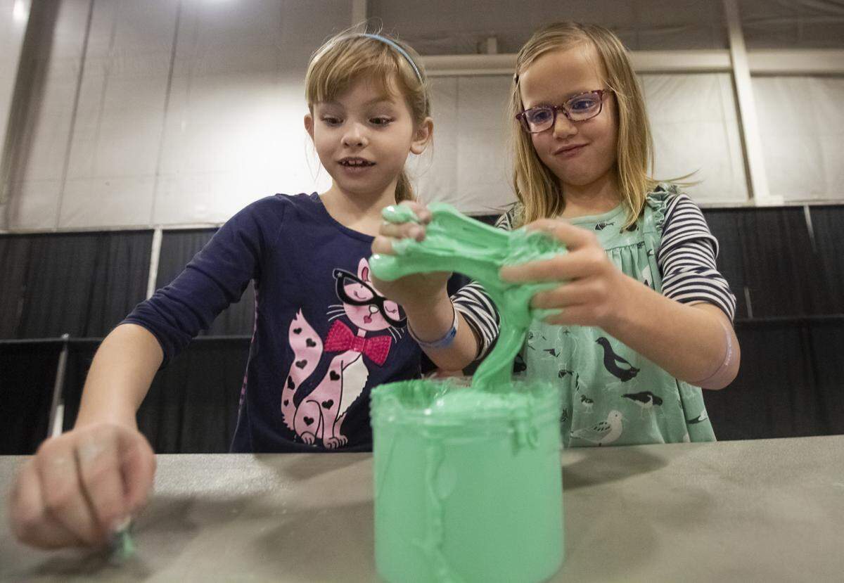 Mia Fox and Zoey Flieger, both 7, play with sticky slime that smells like apples during Slime in the 509 in Pasco. Mia was with her mother, Beth Fox of West Richland, and Zoey was with her mom, Kristi Flieger of West Richland.