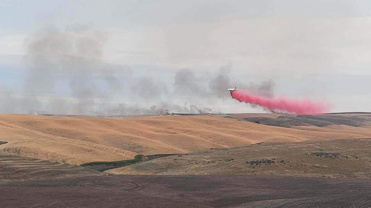 A plane puts retardant down on the blaze burning along the Walla Walla River.