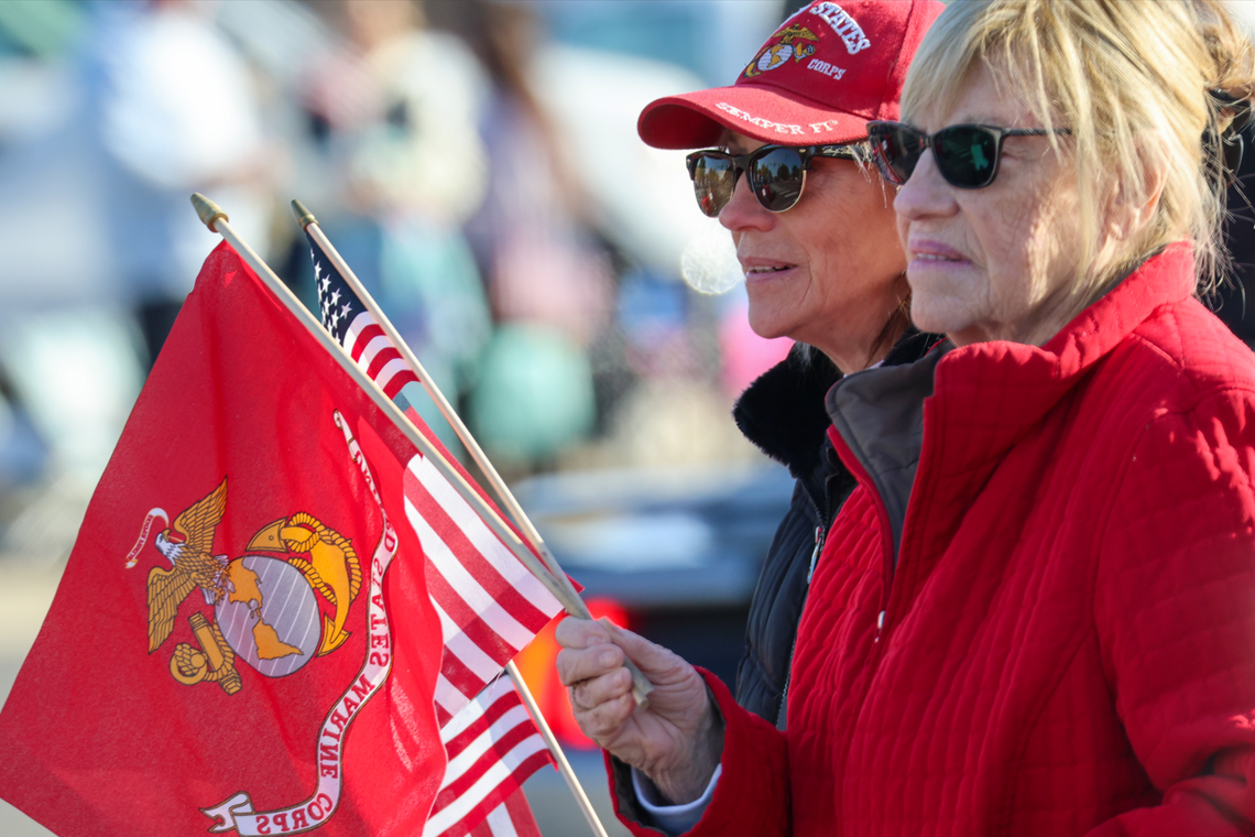Two spectators wave U.S. and Marine Corps flags in honor of veterans during the 26th annual Tri-Cities Veterans Day Parade in West Richland, Wash., on Saturday, Nov. 8, 2025.