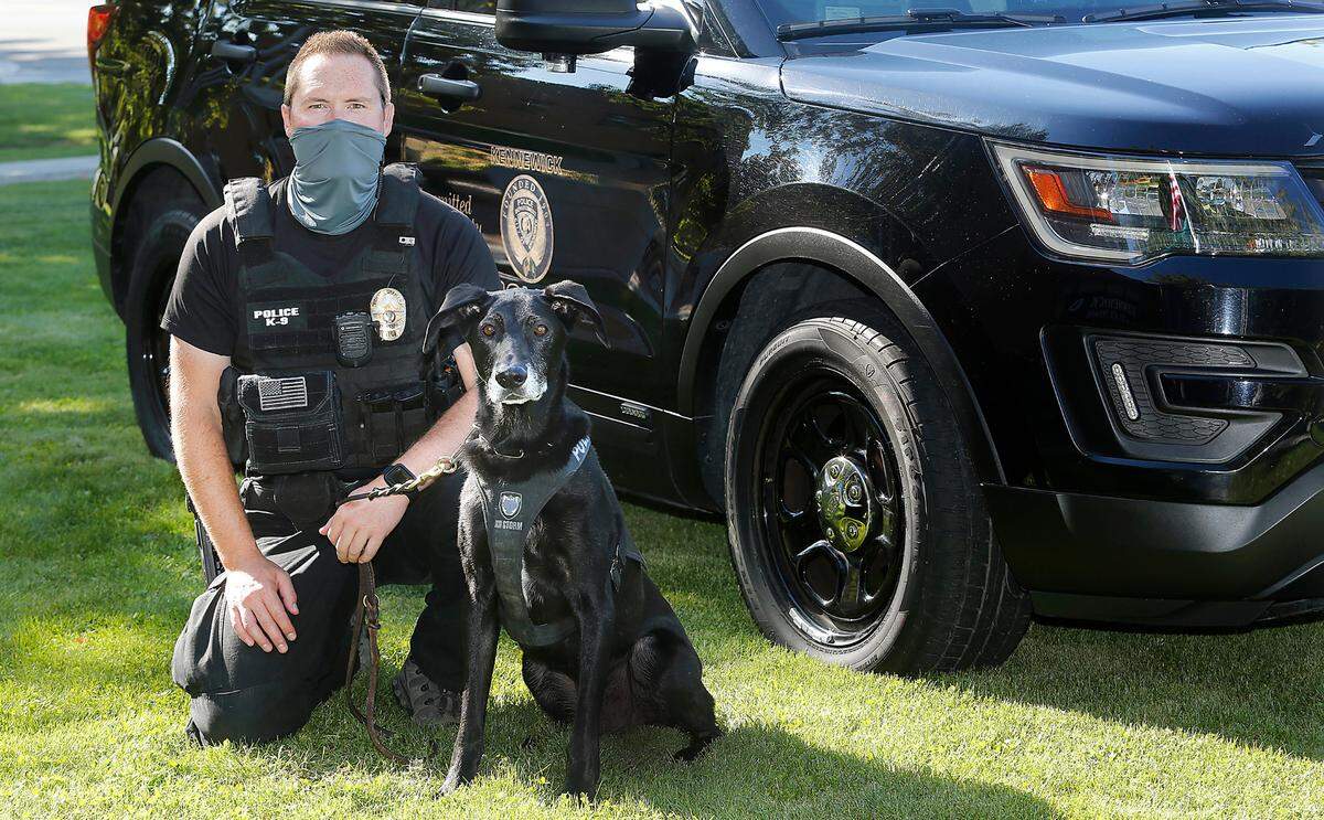 Police officer Isaac Merkl and Bear, a narcotics detection dog, pose for a portrait on the K9’s recent retirement day after 7 years of service at the Kennewick Police Department.
