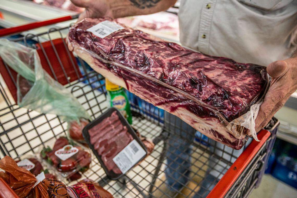 A customer browses through fresh meat cuts at the Kennewick Red Apple Market in May 2020.