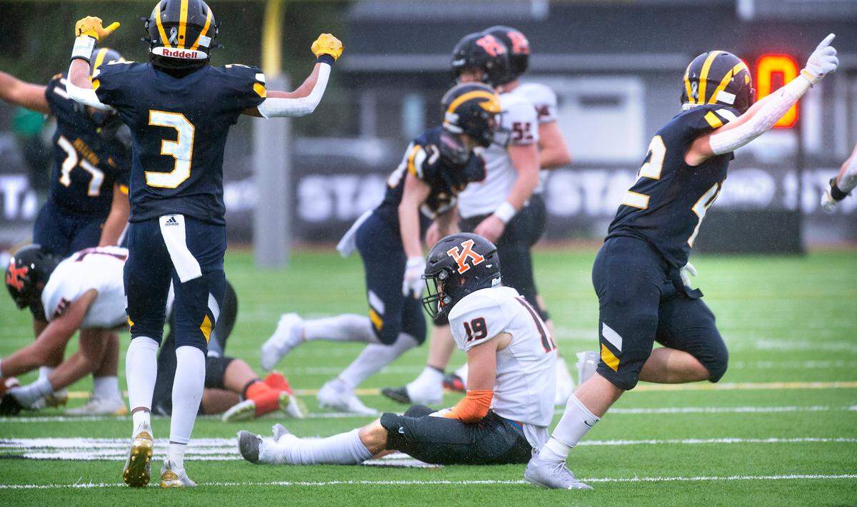 Kennewick senior wide receiver Austin Stoddard sits on the turf as Bellevue players celebrate a late-game interception during Saturday afternoon’s 3A football state championship game at Sparks Stadium in Puyallup, Washington, on Dec. 4, 2021. Bellevue won the title, 17-13.