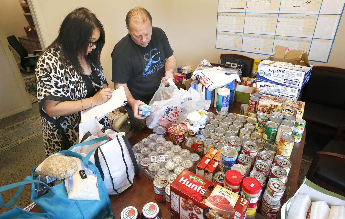 Volunteers SaLee Charlesworth, left, and Chris Hinkley work together bagging household and personal hygiene supplies and food for delivery to isolated seniors in the Tri-Cities. They are part the Helping Hands for Seniors TC project which recently formed in response to coronavirus outbreak. They identifying and helping isolated seniors who do not have an extended support safety network. To donate or help a senior citizen get supplies call: (509) 627-2522. Learn more by watching a video at: tricityherald.com/videos