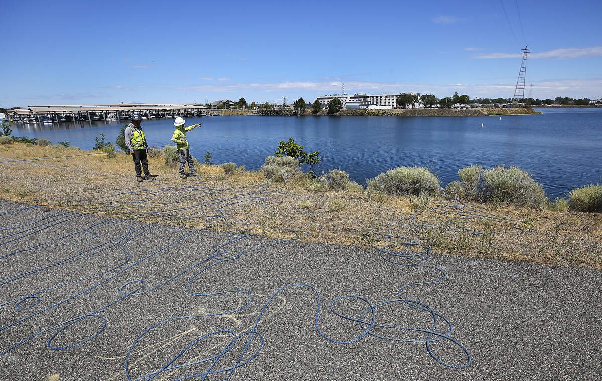 Coils of slack rope cover the Kennewick shoreline walking path Tuesday morning as workers from DJ's Electrical prepare to use a boat to pull the rope, across the Columbia River, to be used in the process of replacing the high tension power line damaged by last week's floatplane crash.