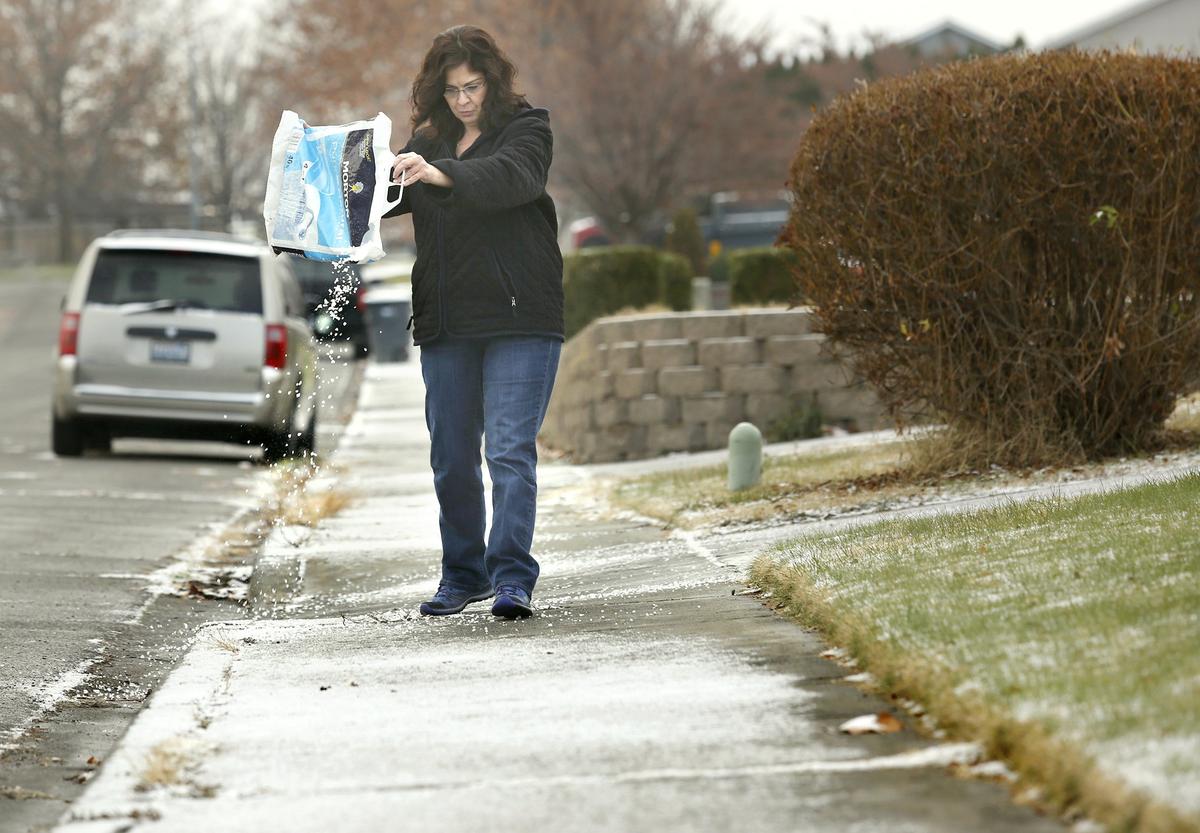 Arminda Hall pours the last of a bag of salt onto the icy sidewalk Monday morning in front of her home in the 1600 block of South Olympia Place in Kennewick. An overnight winter storm coated much of the Mid-Columbia with snow and freezing rain causing many school districts to delay the start of the school day by two hours.
