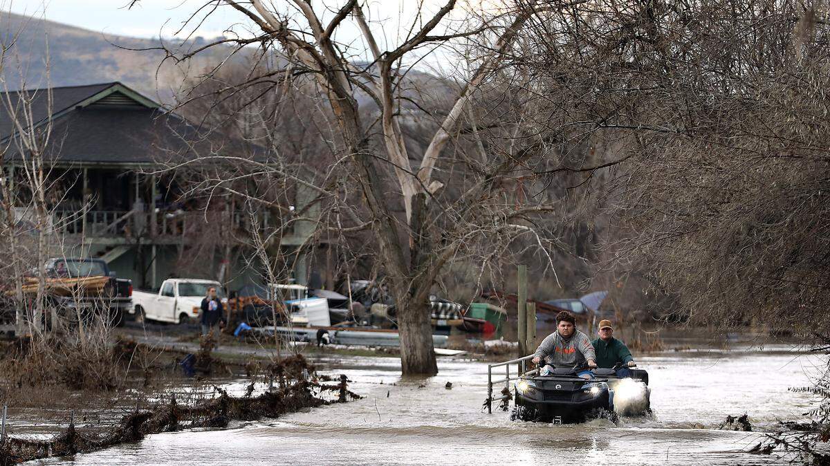 Wyatt Eller, 24, is followed by his brother, Isaac, 19, as they ride four-wheelers through Yakima River floodwater covering the drive to their house off West Van Giesen Street near Buckskin Lane Monday in Richland.