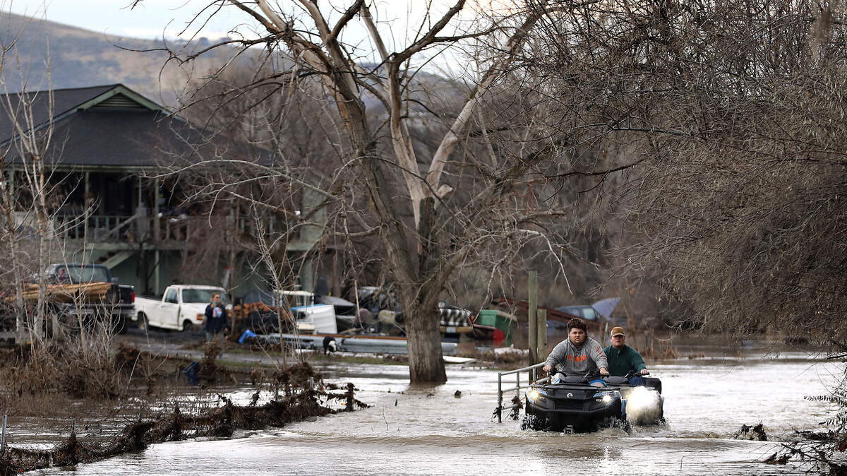 Wyatt Eller, 24, is followed by his brother, Isaac, 19, as they ride four-wheelers through Yakima River floodwater covering the driveway to their house off West Van Giesen Street near Buckskin Lane Monday morning in Richland. They said their home, situated on high ground, stayed dry over the weekend when the river crested. They hopped into a pickup, parked on nearby high ground before the flood peaked, to get cleaned up at a relatives home because their septic system is impacted by the floodwaters.