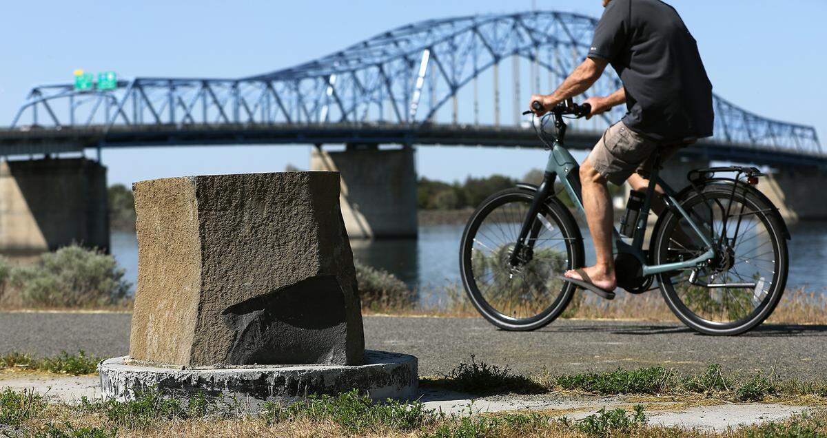A bicyclist rides past a recently installed basalt marker just downstream of the blue bridge in Kennewick.