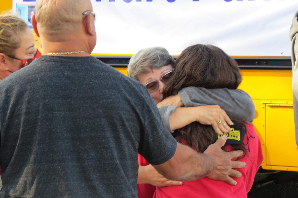 Nancy Lenhart was greeted with a hug when she got off of a school bus with her family in front of Longfellow Elementary School Saturday.