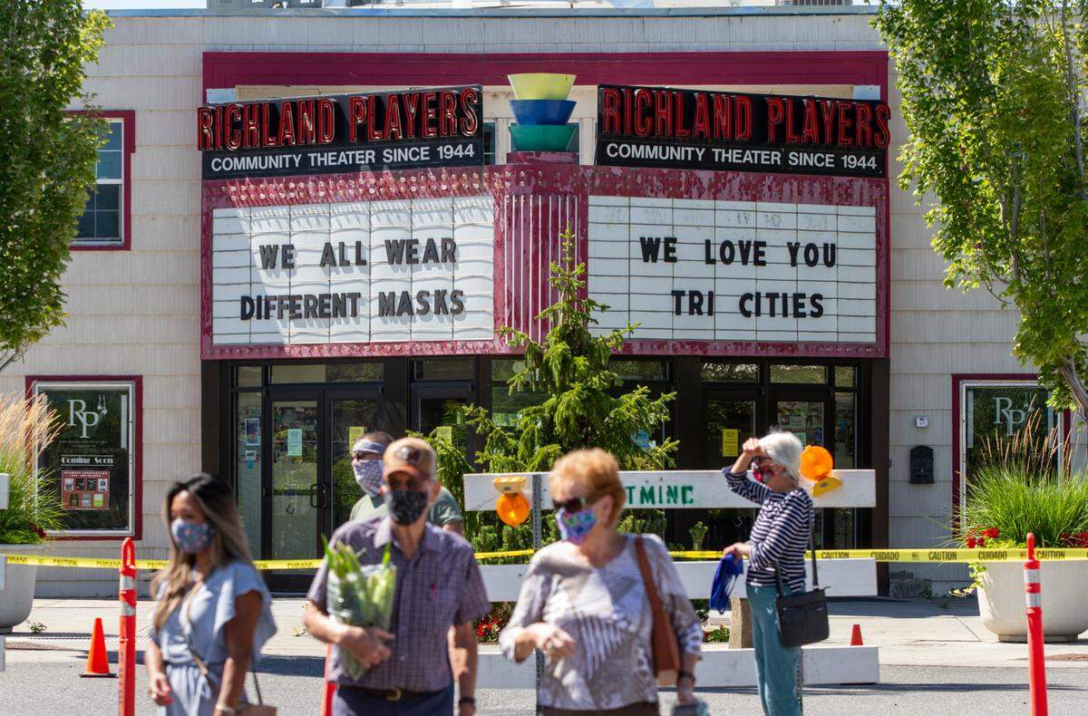 As people mill around the Richland Farmers Market, the marquee outside of the Richland Players community theater displays messages to encourage people in the Tri-Cities to wear masks and social distance to help prevent the spread of the coronavirus.