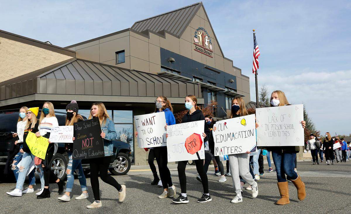 Several hundred students march around the Kennewick School District administrative offices parking lot Wednesday morning calling for the return of in-person learning following a recent decision by the school board to delay opening middle and high schools until Feb. 2.