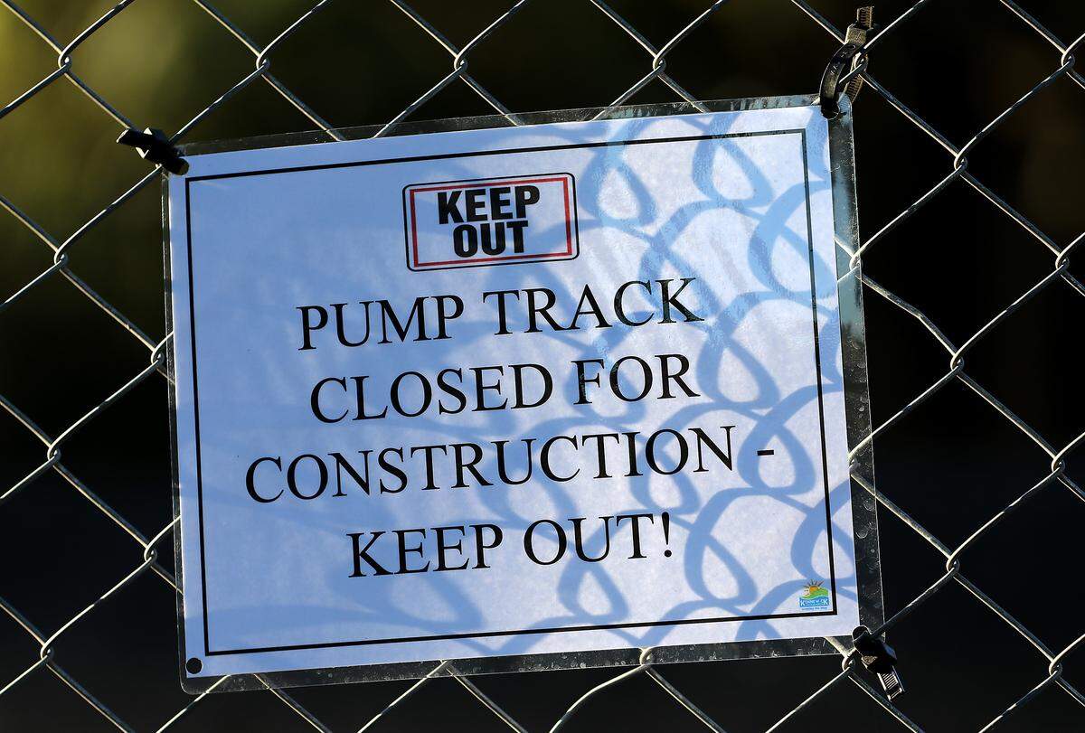 Sign on the temporary construction fencing surrounding the bicycle pump track being installed.