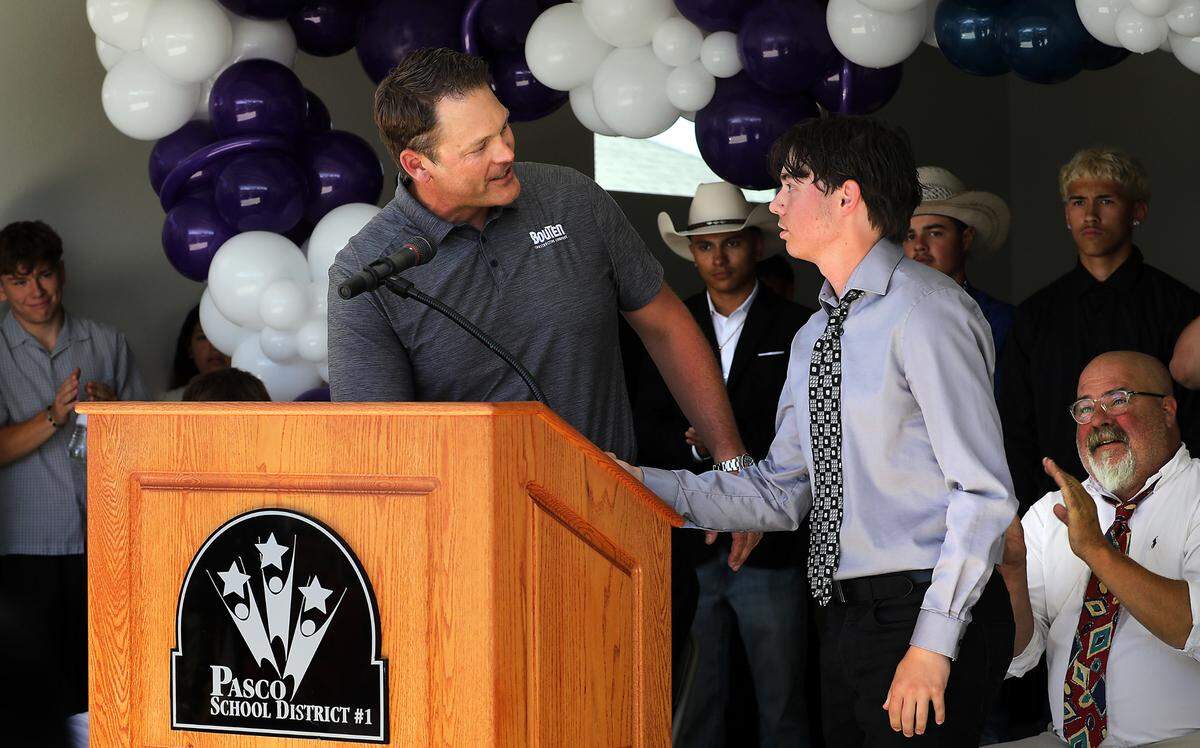 Chiawana High School student Gavin Frank, right, is recognized by Brandon Potts, of Bouten Contstruction Company during the dedication of the 25th Team Pasco House.