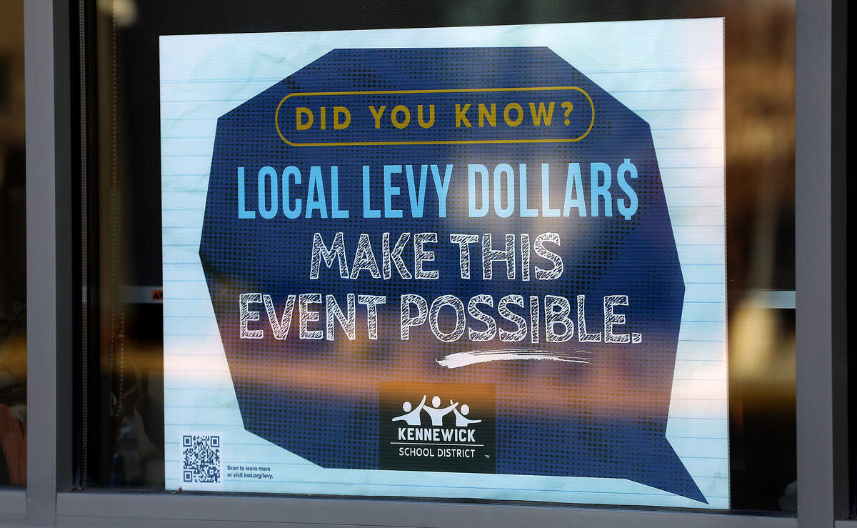 An informational sign about local school levies is displayed in a window of the main office at Amistad Elementary School in Kennewick.