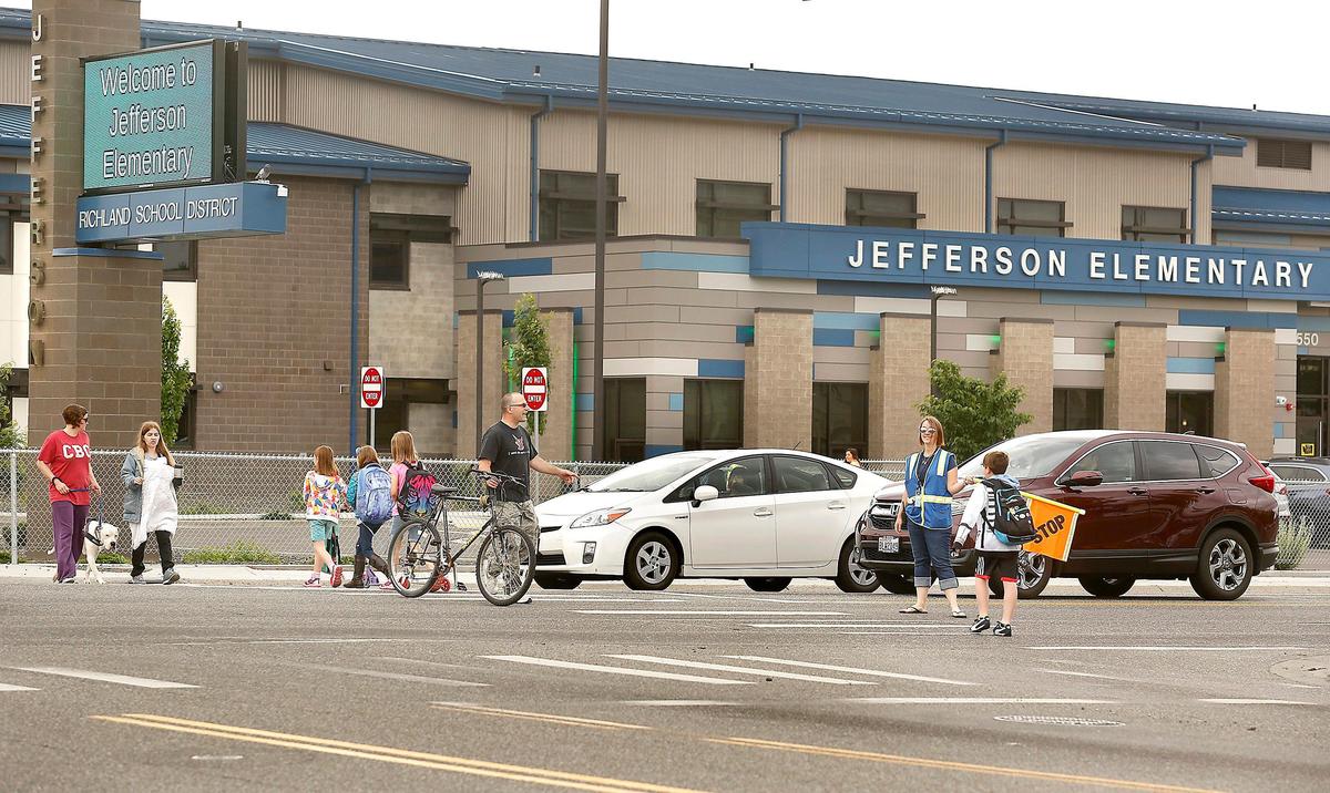 Crossing guard Sarah Griffiths holds her warning flag for students and parents at Jefferson Elementary School to safely cross George Washington Way in Richland.