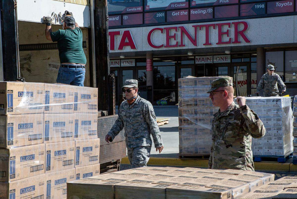 Members of the National Guard and workers from the Toyota Center work to set up for the distribution of 700 boxes of food from 2nd Harvest to the Tri-Cities community.