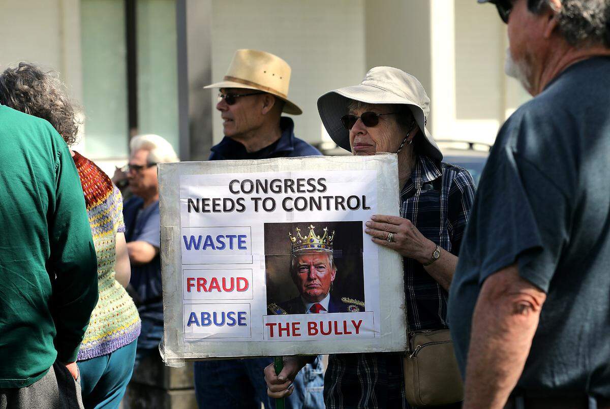 Julie Epperly of Kennewick holds a sign outside the Richland office of Rep. Dan Newhouse, R-Wash., during Wednesday’s rally.