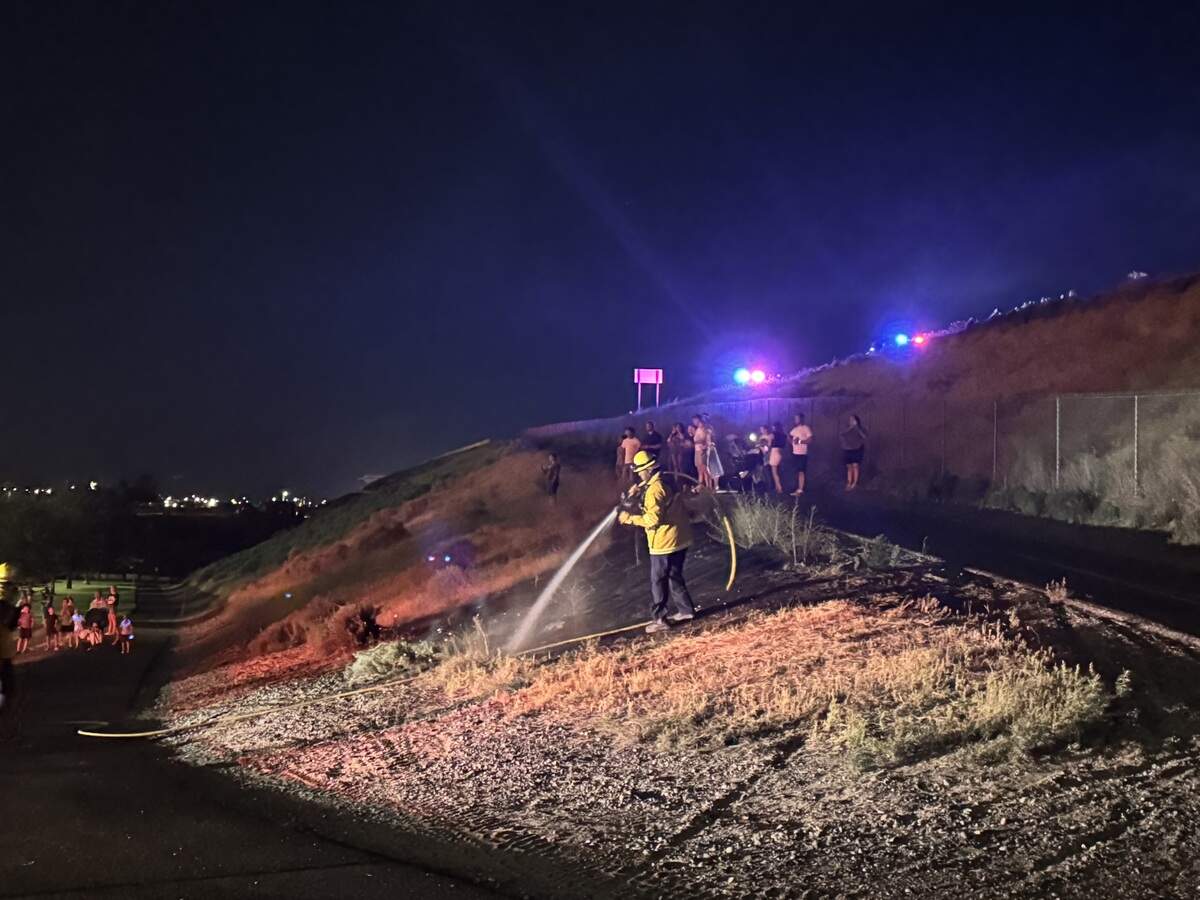 A firefighter puts out a small brush fire started by fireworks on the walking trail up to the Interstate 182 bridge at Columbia Point Marina Park.