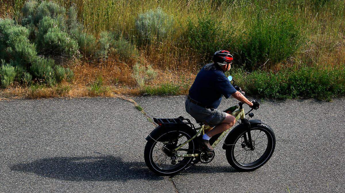 A cyclist zips along the paved trail near Richland’s Bateman Island on a battery-powered electric bicycle in 2023.