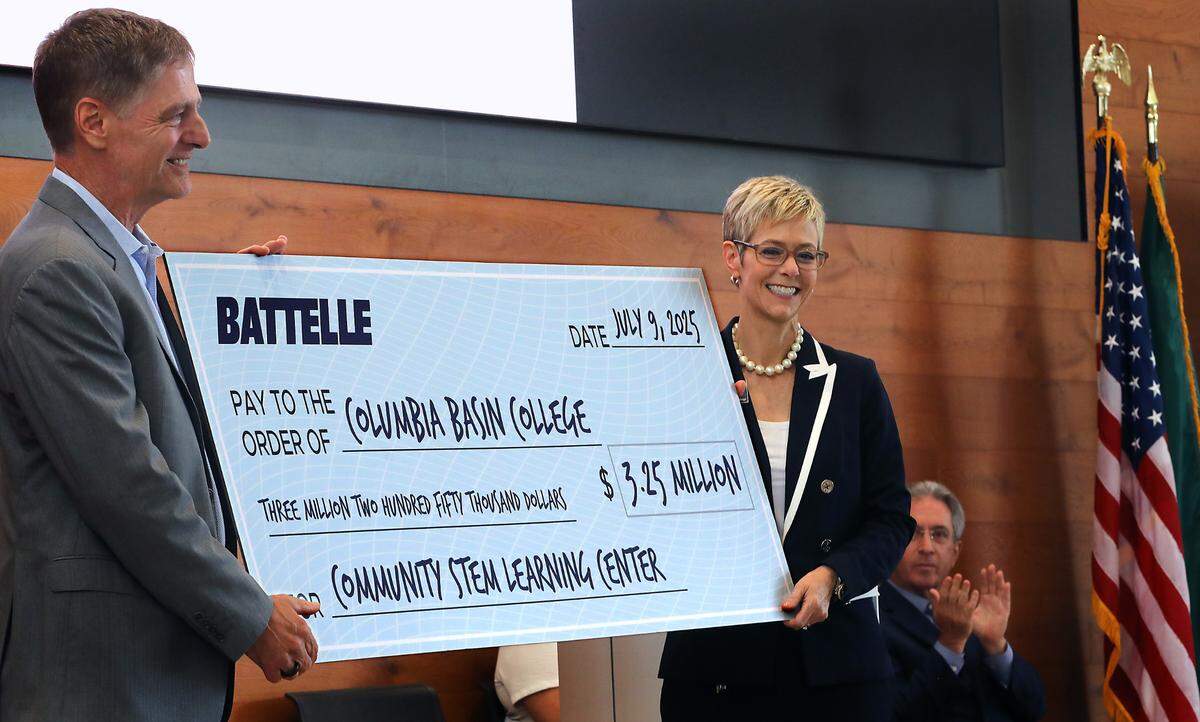 Rebekah Woods, president of Columbia Basin College, accepts a $3.25 million check from Lou Von Thaer, Battelle President and CEO, during a ceremony Wednesday in Richland.