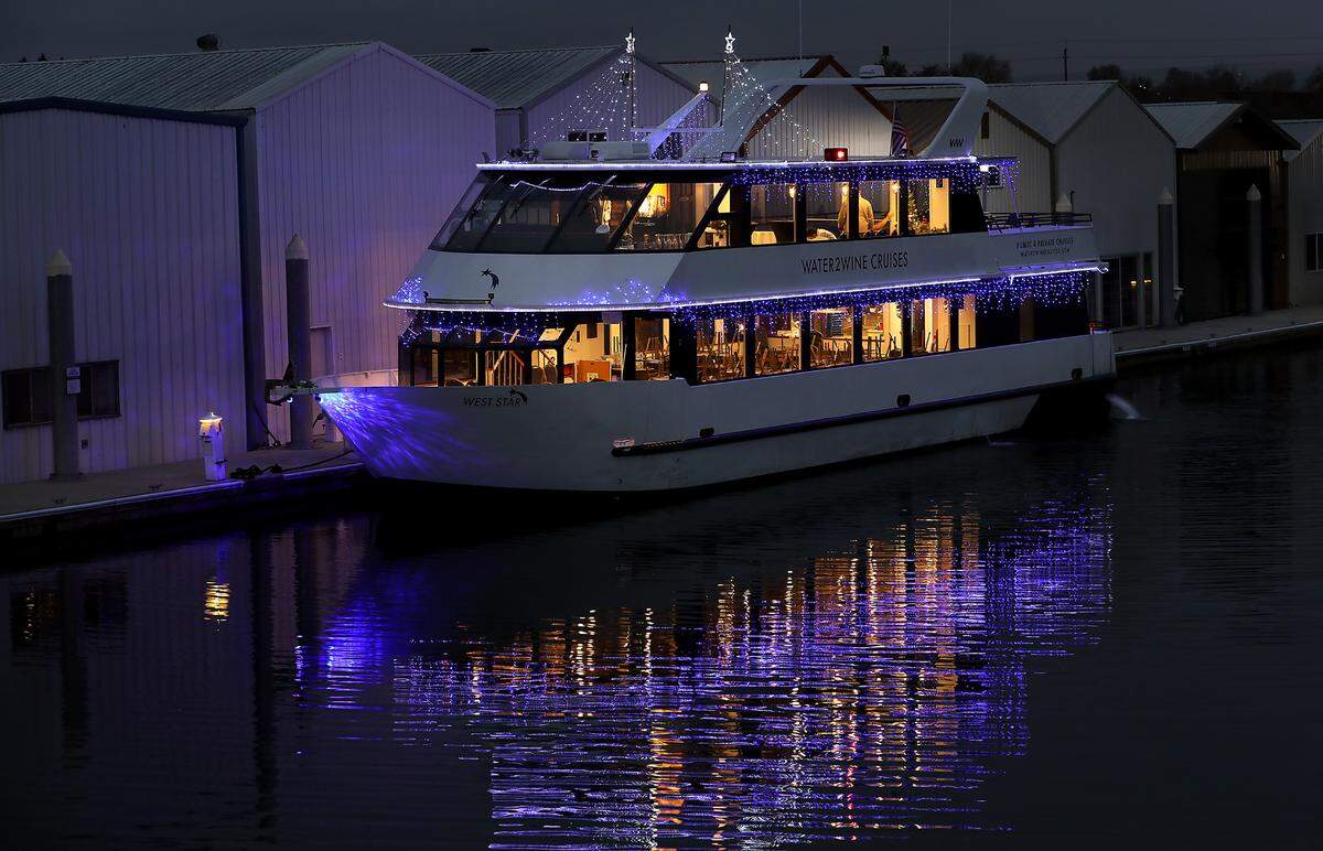 Christmas lights reflect off the water from the Water2wine Cruises West Star 74-foot luxury yacht docked at the Port of Kennewick facility on Clover Island in Kennewick. It offers private cruises during the annual lighted Christmas boat parade.