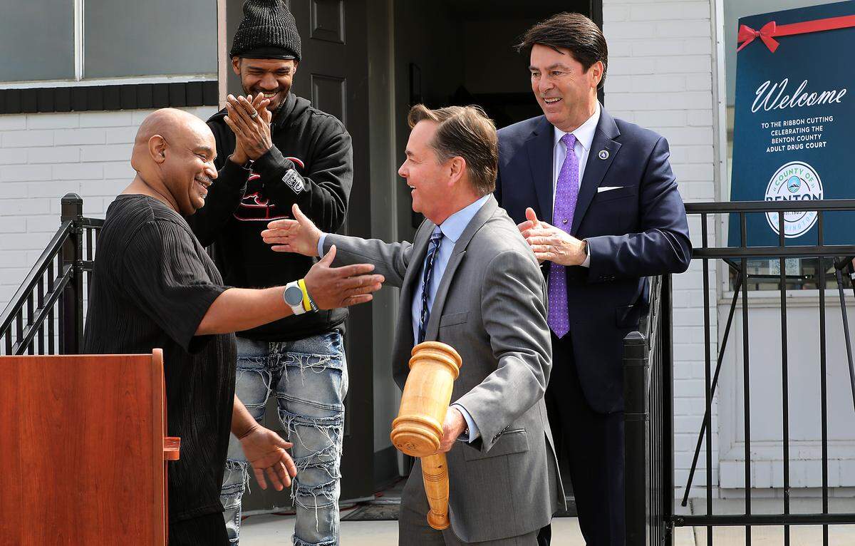 Benton County Superior Court Judge Joe Burrowes is surprised with an oversized gavel during Friday's ribbon cutting ceremony for The Benton County Adult Drug Court's new office at 901 S. Auburn St. in Kennewick. Program alumni George Talley, left, and Zell Hughes made the surprise presentation. Michael Alvarez, a Benton County commissioner, is at right.