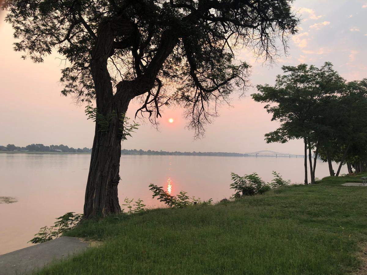 The sun casts a fiery glow on the Columbia River in Kennewick through the smoke from distant forest fires.