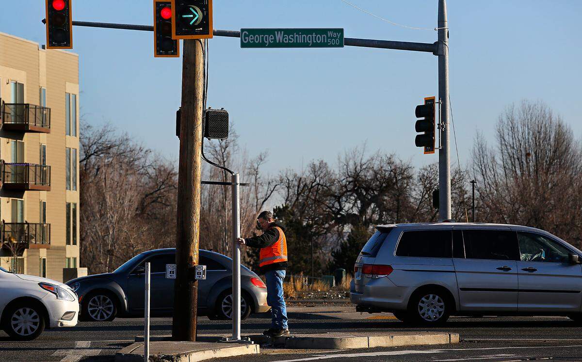 A city of Richland energy services employee checks the temporary repairs made to a traffic signal on George Washington Way at Jadwin Avenue. The metal support pole was sheared off Sunday morning by a suspected drunk driver.