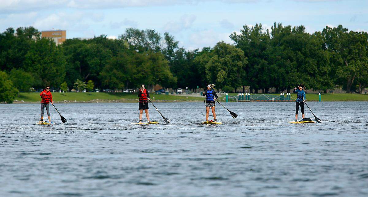 With the wind at their backs and the current propelling them down the Columbia River, this group of paddle boarders swiftly glides past Richland’s Howard Amon Park under partly sunny skies in Richland.