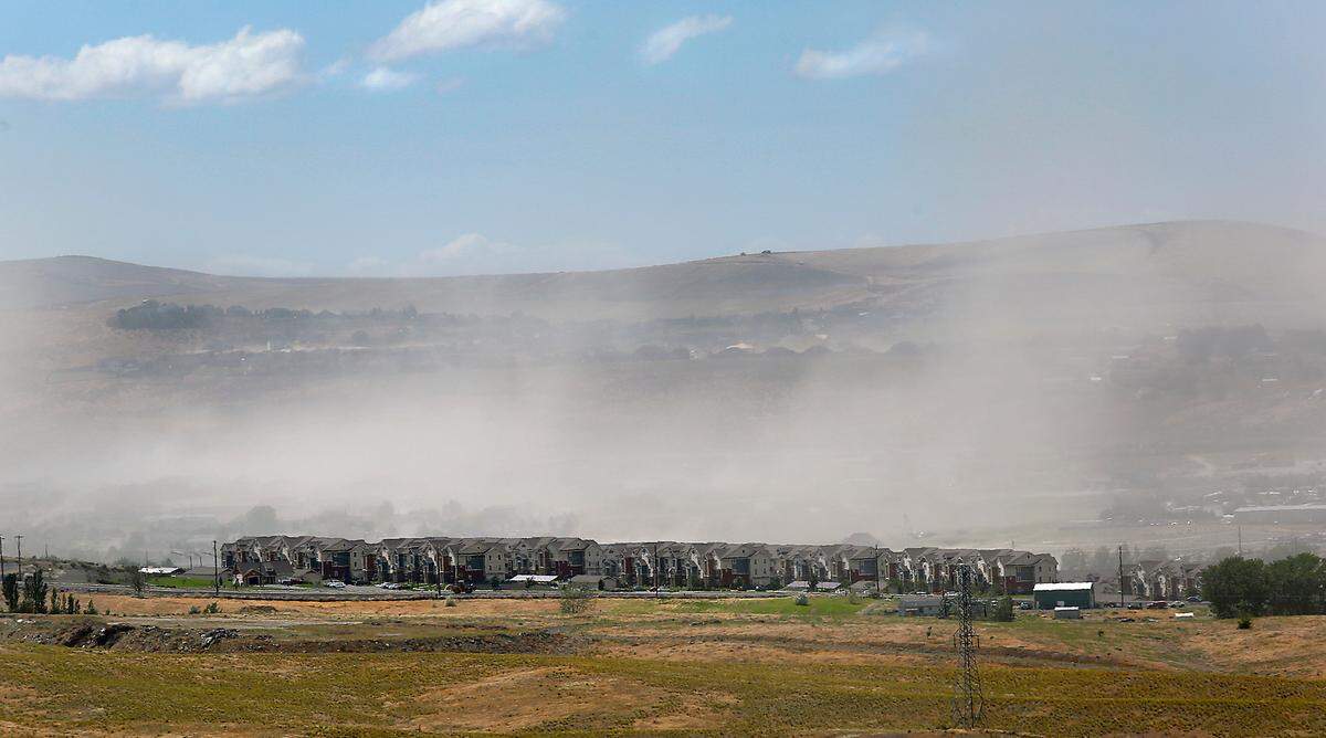 Waves of windblown dust clog the air Thursday behind the Badger Canyon Apartment complex in Kennewick.
