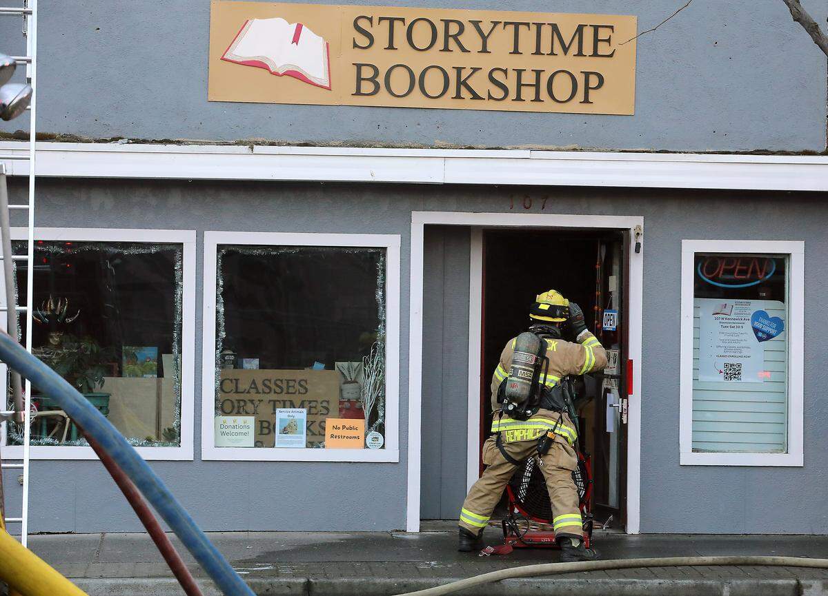 A firefighter positions a fan in the front door of the Storytime Bookshop as firefighters from around the Tri-Cities work early Tuesday morning to extinguish a fire at the El Tequilas Restaurant in downtown Kennewick. 