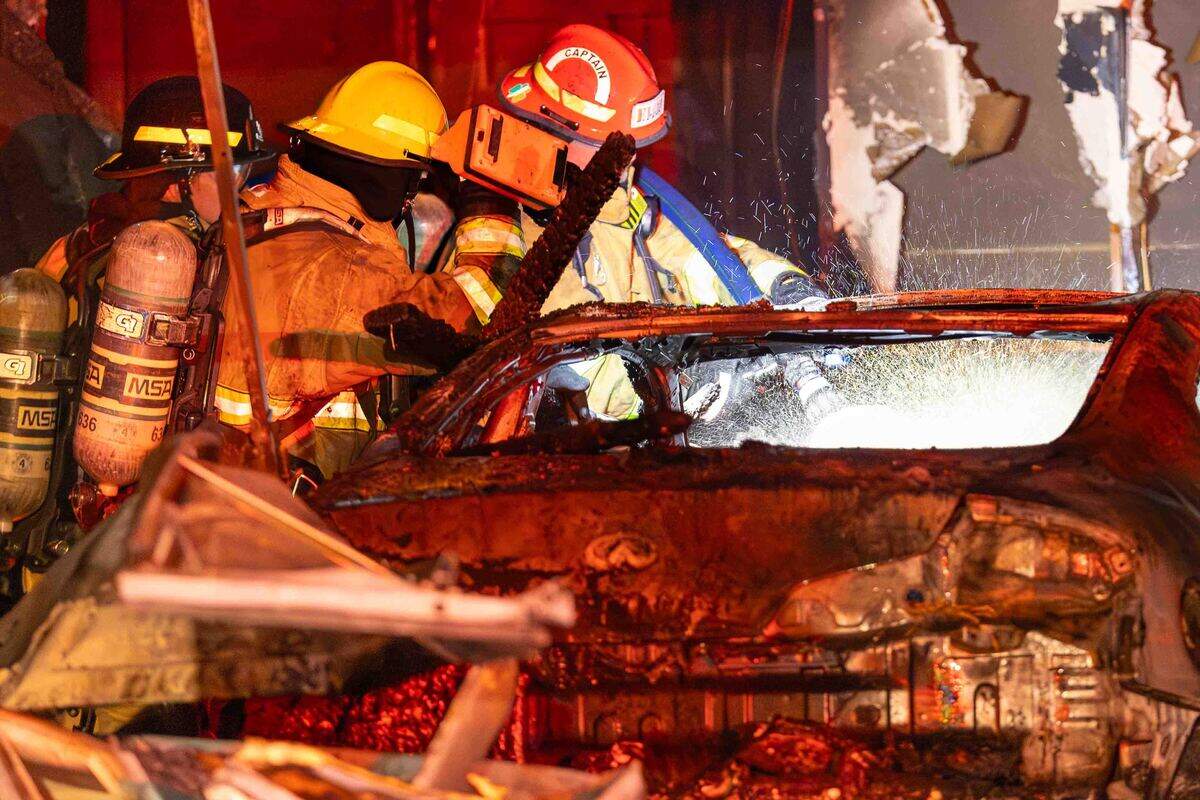 Firefighters direct water onto a vehicle inside the garage while extinguishing an early morning residential fire in the 5200 block of Jacksnipe Court on Sunday in West Richland. The vehicle was destroyed in the fire.