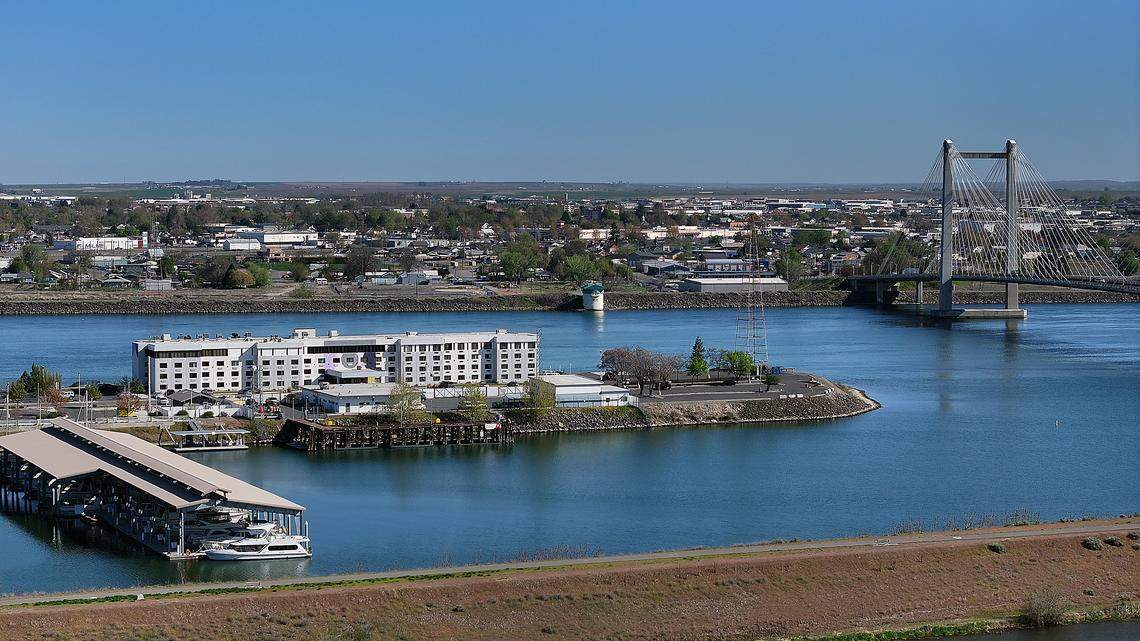 Kennewick’s historic Clover Island with Spark by Hilton hotel, U.S. Coast Guard station, Clover Island Yacht Club boathouses and the cable bridge over the Columbia River in Kennewick. Photo taken on April 8, 2026.
