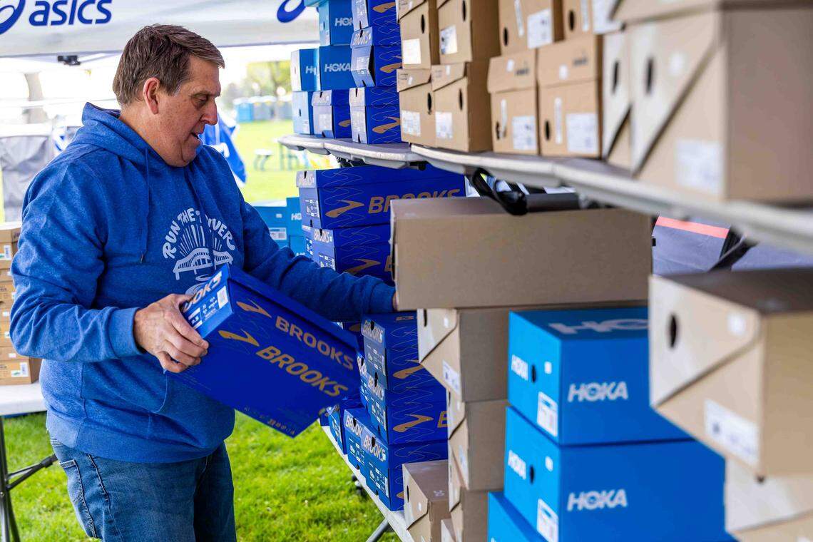 Scott Conrad, owner of Runner’s Soul of Tri-Cities and event sponsor, organizes running shoes at a vendor booth during the Run the River Marathon, Saturday, April 18, 2026, at Columbia Park in Kennewick.