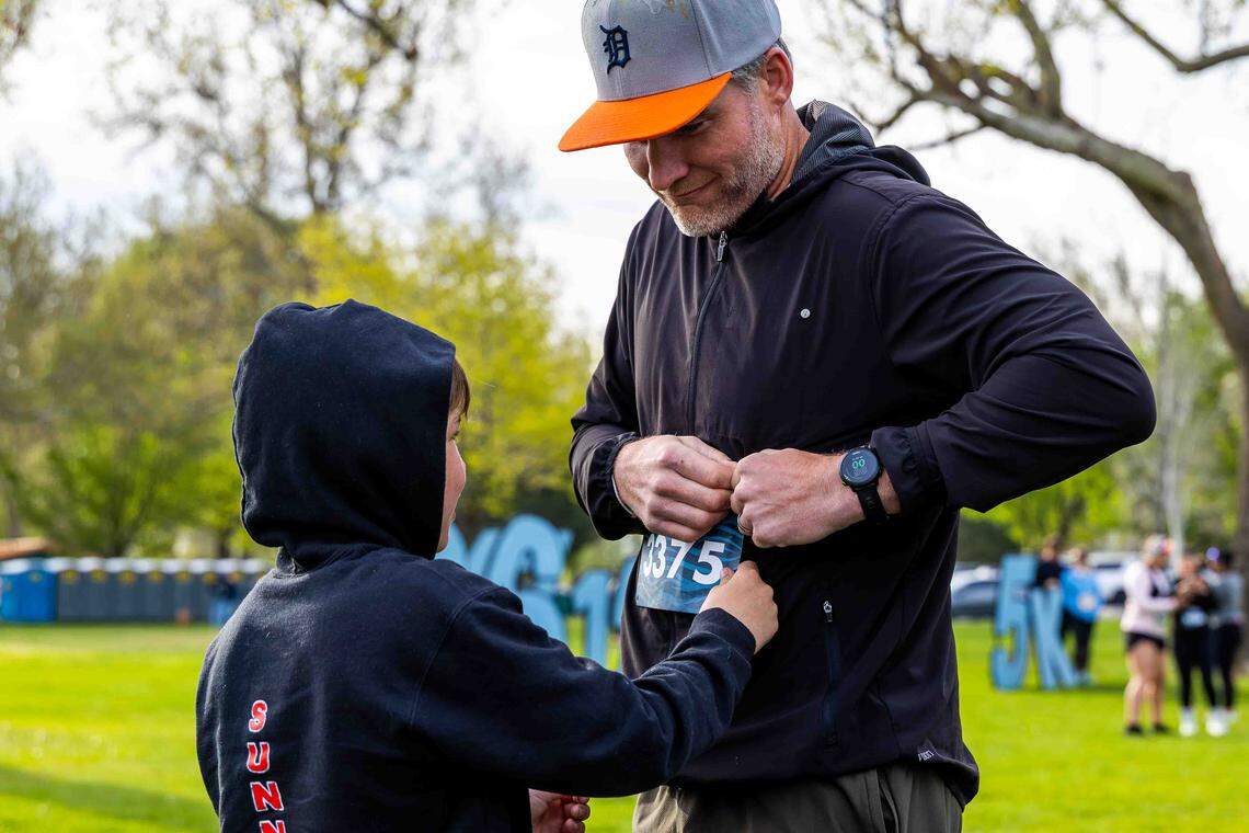 Luke Lobbestael, 10, of Zillah, helps his father, John Lobbestael, pin on his race bib before the Run the River race Saturday, April 18, 2026, at Columbia Park in Kennewick. John Lobbestael was running his first half-marathon and plans to run a full marathon later this year.